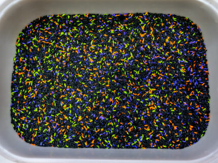 Halloween Bear Sensory Bin with colorful Halloween rice, costumed bears, ghosts, spider, pom-poms, gems, pumpkin container and wooden scoop