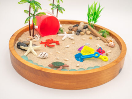 Beach Sensory Bin with Sand featuring real shells, sea creatures, palm trees, scoops, sifters, rocks, and red bucket for ocean sensory play