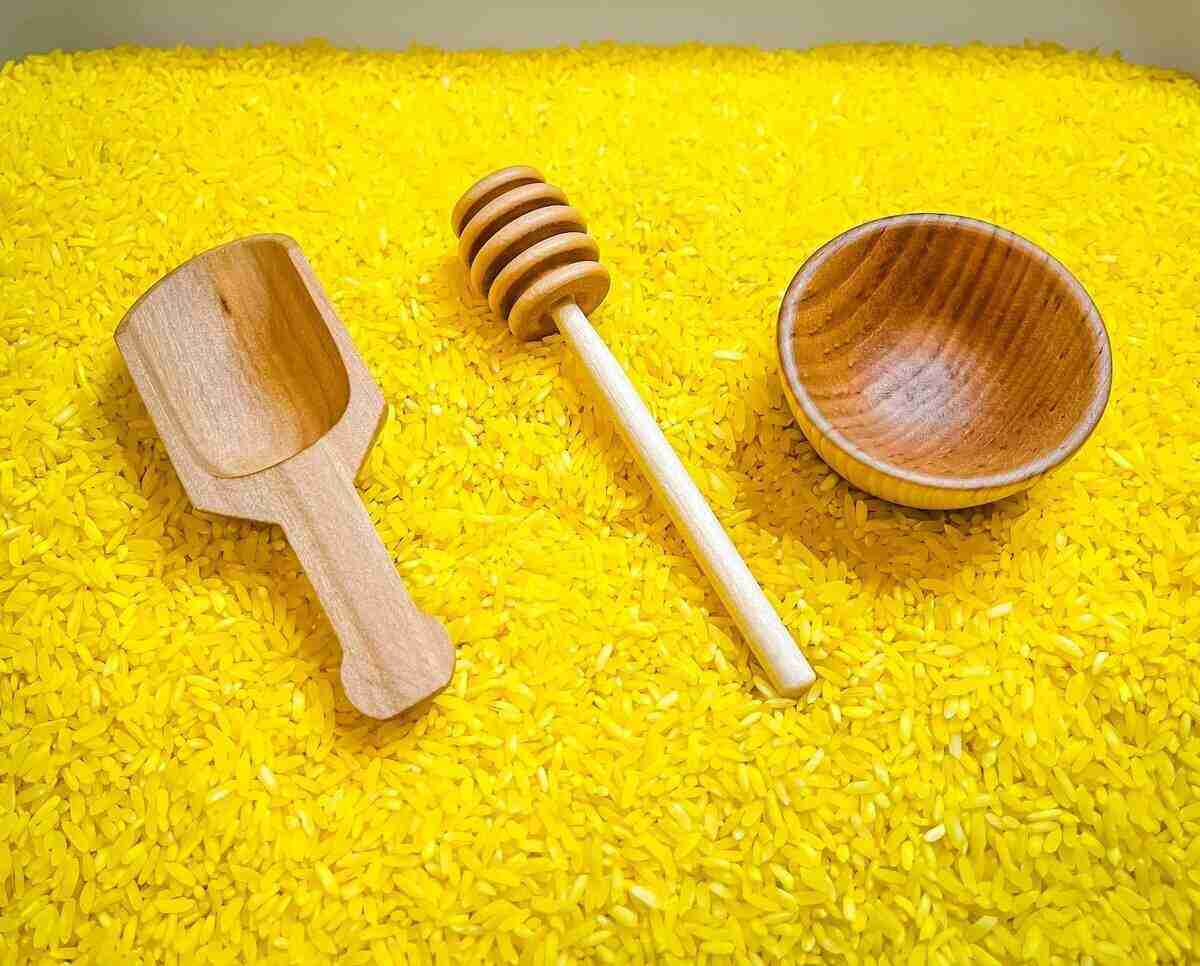 A wooden spoon and bowl on yellow rice
