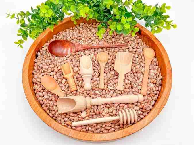 A bowl of beans with wooden spoons and spoons