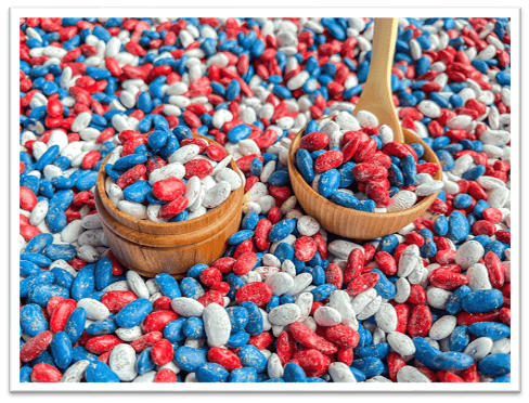 A bowl and spoon in a pile of red white and blue beans
