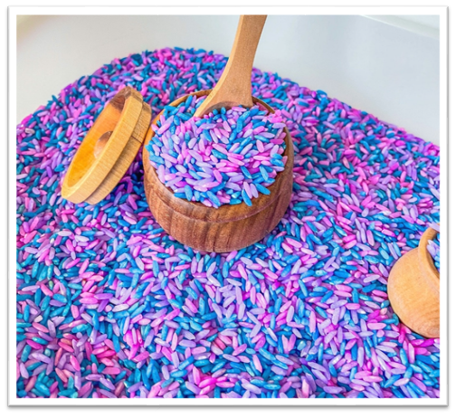 A bowl of colored rice with a spoon in it
