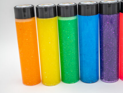 Six glitter calming bottles in pink, orange, yellow, green, blue, and purple with sparkly glitter