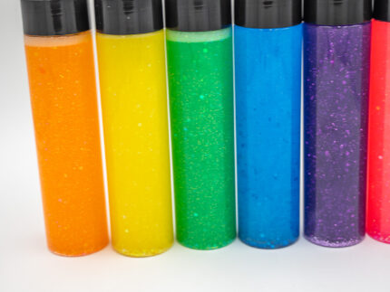 Six glitter calming bottles in pink, orange, yellow, green, blue, and purple with sparkly glitter