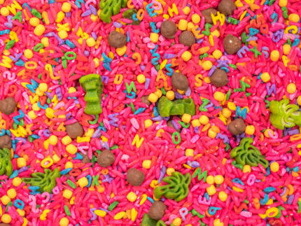 Chicka Chicka Alphabet Sensory Bin with colorful sensory filler, alphabet letters, coconut container, palm trees, pom-pom coconuts and wooden scoop