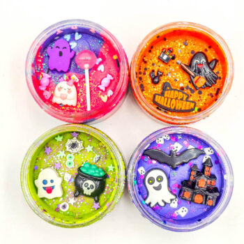 Four Halloween playdough jars with glitter and ghost, bat, cauldron, and haunted house charms