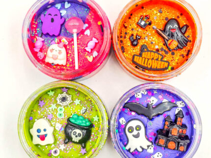 Four Halloween playdough jars with glitter and ghost, bat, cauldron, and haunted house charms