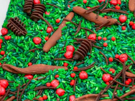 Holly Woods Sensory Filler with green rice, red berry-inspired accents, and brown woodland pieces for Christmas sensory play