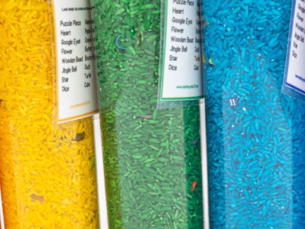 I Spy Bottles filled with rainbow colored rice and hidden items, with laminated word lists and picture cards