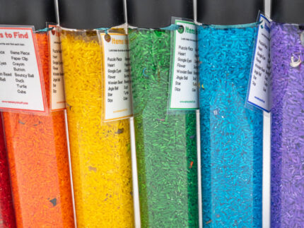 I Spy Bottles filled with rainbow colored rice and hidden items, with laminated word lists and picture cards