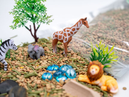 Safari Budget Bag with split peas, dyed pasta, lion, giraffe, elephant, zebra, tree, bushes, rocks, blue flat-back marbles, and wooden scoop