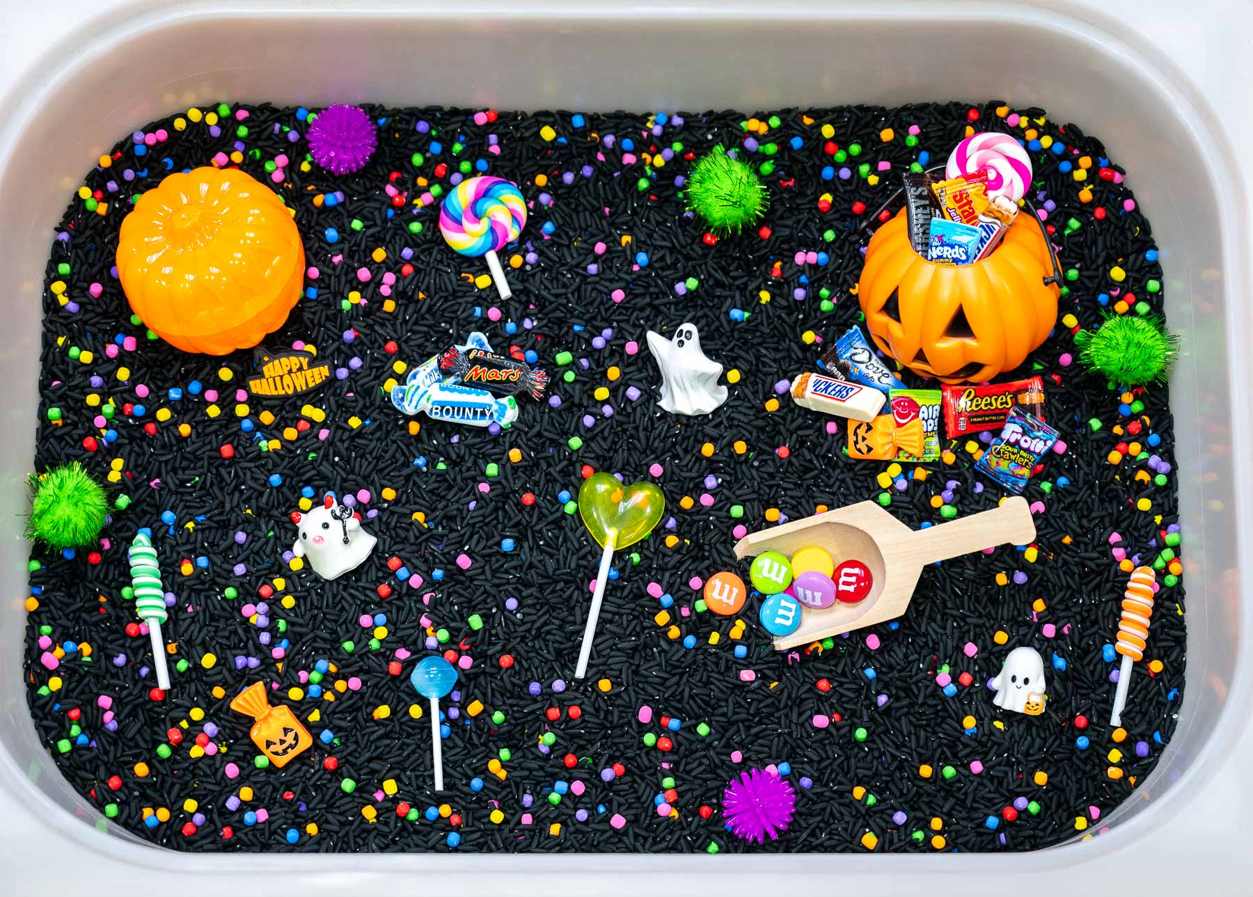 Trick-Or-treat Sensory Bin-1 Trick-or-Treat Sensory Bin with black rice, rainbow couscous, pumpkin containers, pretend candy, ghosts, pom-poms, and wooden scoop